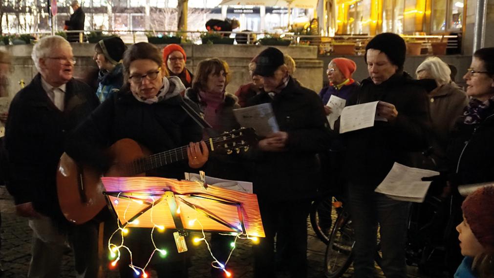 Singen am Abend vor der Thomaskirche im Schein der Lichterketten