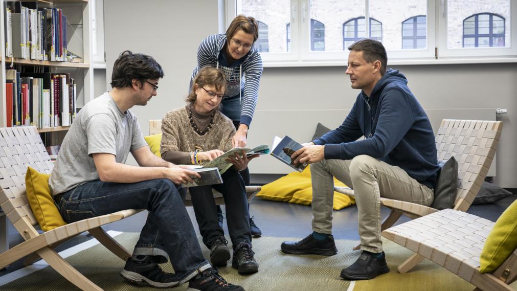 Gruppe im LeipzigZimmer, sitzt in Lounge-Sesseln und diskutiert