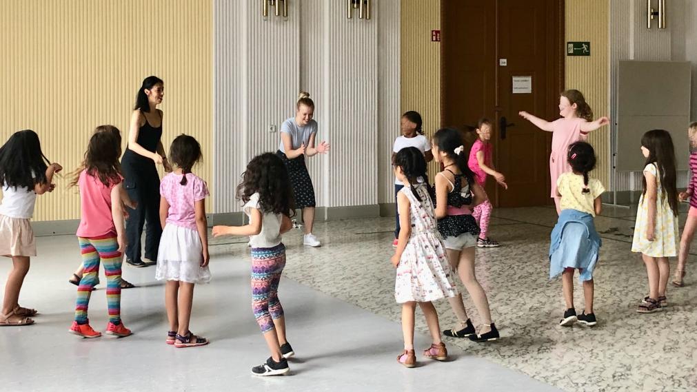 Kinder tanzen im Kreis mit Tanzpädagoginnen